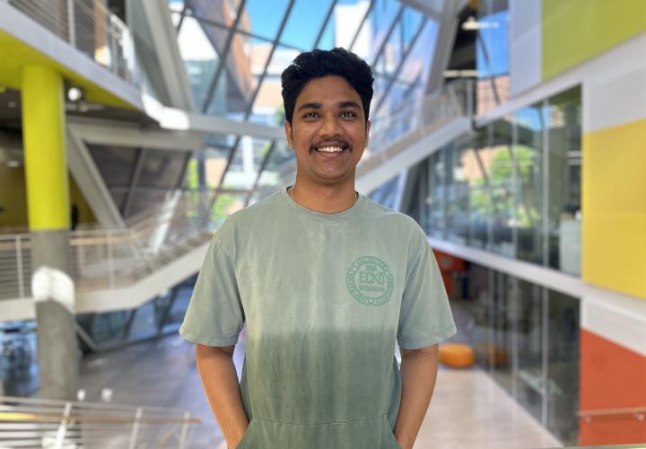 Student stands and poses for a headshot in the Karl Miller Center Atrium.