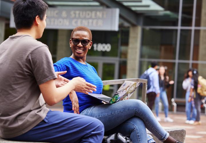 Students sitting in front of building.