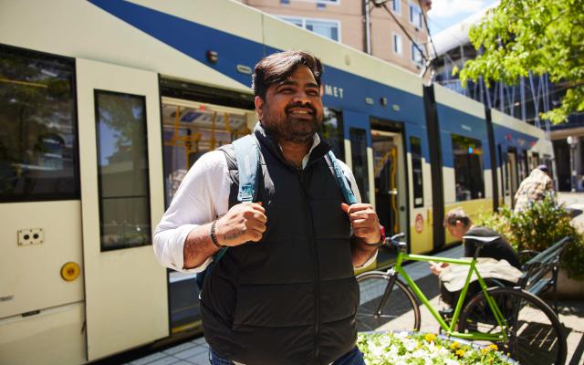 Student stands in front of a city train.