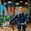 Student with bicycle standing in front of Campus Rec Building