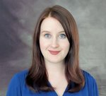A professional photo of Dr. McMahon in a blue button-up blouse on a grey background.