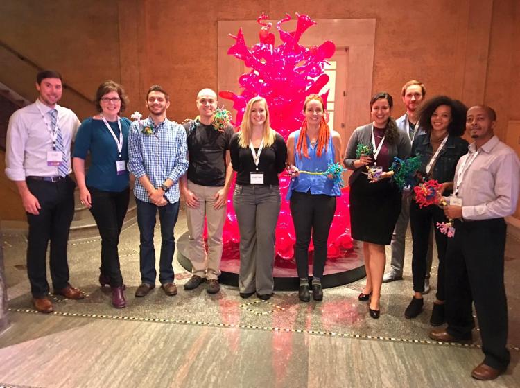 Jaboa Lake standing among other colleagues at the Art and Neuroscience of Change at the Portland Art Museum. They are standing in a gallery in front of a bright pink, abstract figure.