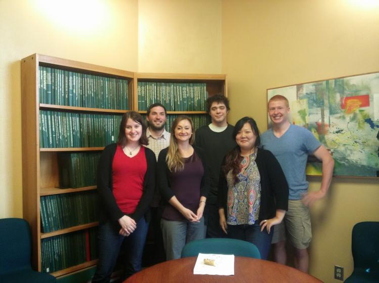 Photo of GRASP lab members in 2014. Dr. Kahn stands with two graduate students and three undergraduate research assistants behind a conference table with a bookshelf and yellow walls in the background.