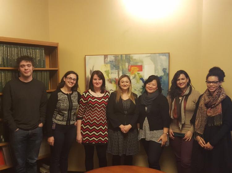 Photo of GRASP lab members in 2015. Dr. Kahn stands with four graduate students and two undergraduate research assistants behind a conference table with a bookshelf, a multi-colored abstract painting, and yellow walls in the background.
