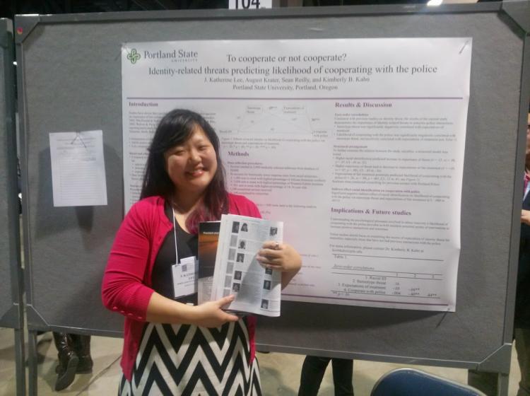 J. Katherine Lee standing in front of her poster at SPSP 2015 annual conference. The poster is titled: "To cooperate or not cooperate? Identity-related threats predicting likelihood of cooperating with police"