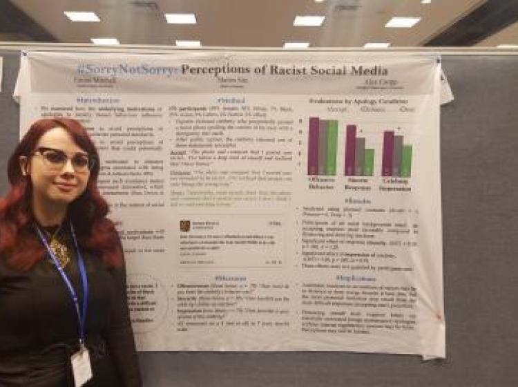 Emma Money standing in front of her poster at SPSP 2018 annual conference. The poster is titled: "# Sorry Not Sorry: Perceptions of Racist Social Media"