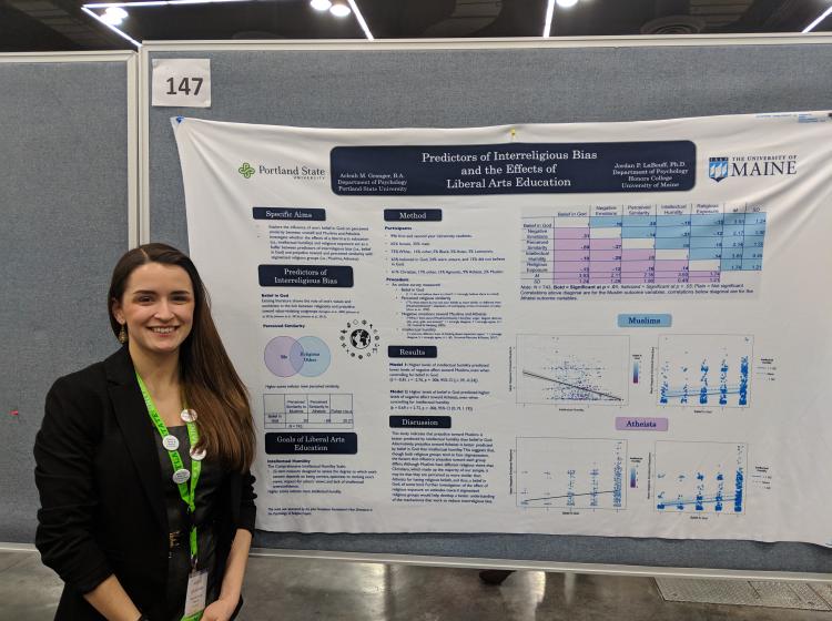 Aeleah Granger standing in front of her poster at SPSP 2019 annual conference. The poster is titled: "Predictors of Interreligious Bias and the Effects of Liberal Arts Education"