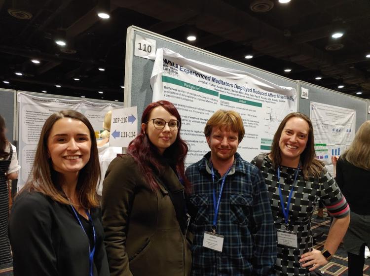 Photo of GRASP Lab members: Aeleah Granger, Emma Money, Jared Cutler, and Danielle Rosenscruggs at SPSP 2020 in New Orleans, LA. They are standing in front of an academic poster titled: "Experienced Meditators Displayed Reduced Affect Misattribution"