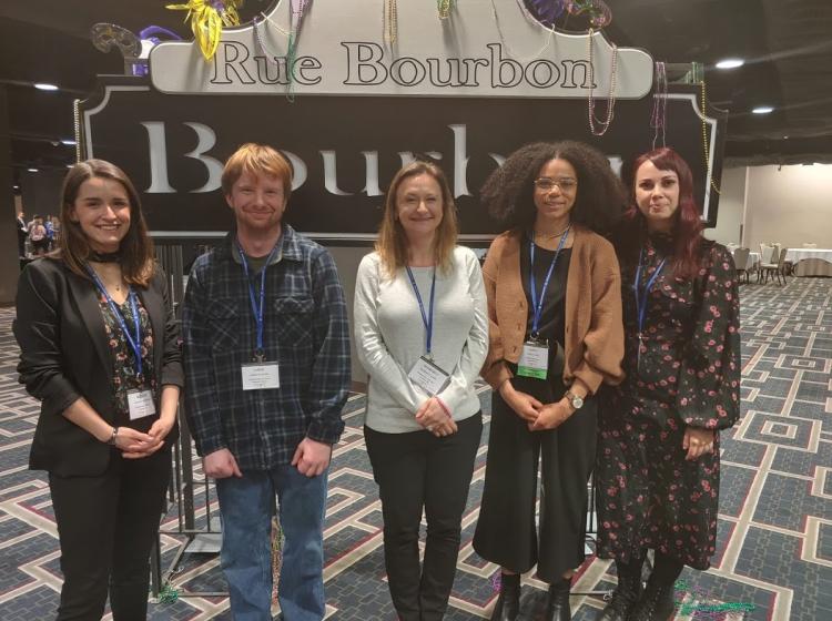 Photo of GRASP lab members in 2020. Dr. Kahn stands with four graduate (Aeleah Granger, Jared Cutler, Jaboa Lake, Emma Money) students in front of a New Orleans, "Rue Bourbon" sign at the SPSP conference in New Orleans, 2020