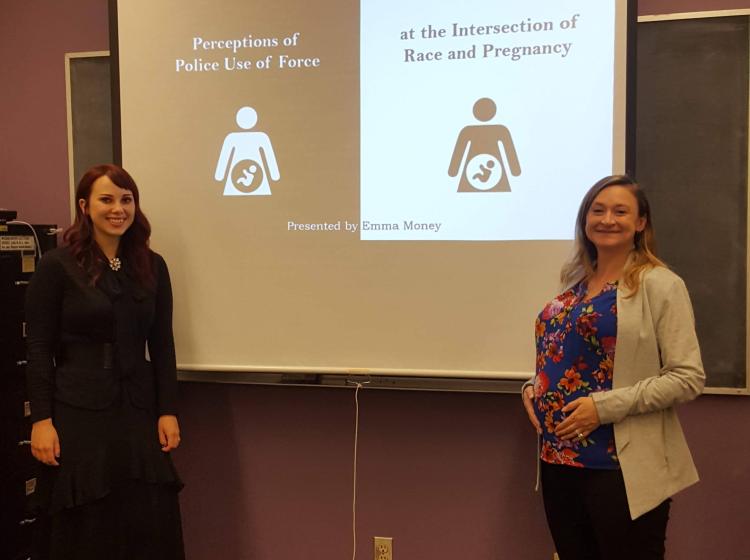 Emma Money and Kimberly Kahn standing in front of Emma's title slide. The title reads "Perceptions of Police Use of Force at the Intersection of Race and Pregnancy". 