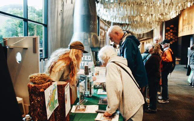 A couple at an exhibit table at OMSI, listening to presenter