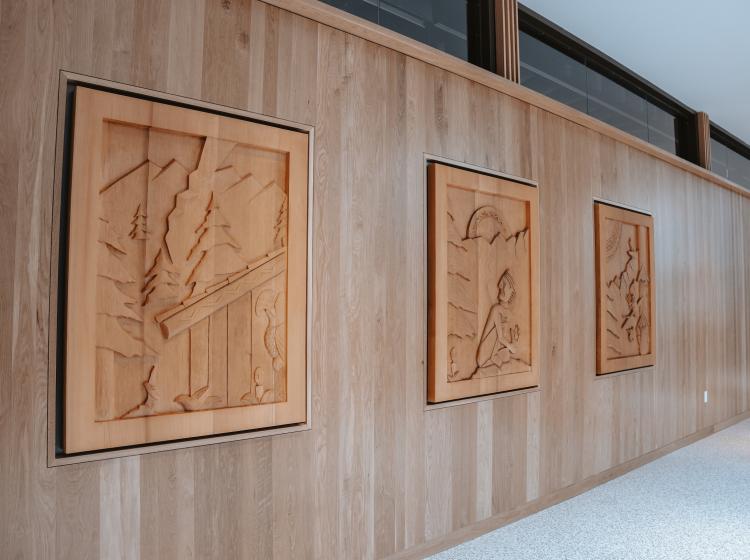 Three wooden carvings on wall by Indigenous artist
