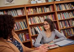 Student and professor seated at table in library