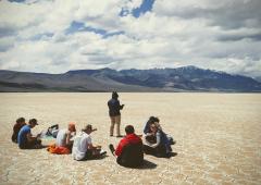 Group of students seated at natural area, with mountains in backdrop
