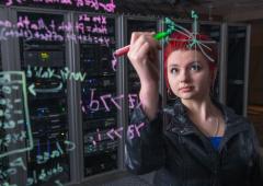 Woman with red hair writing equations on clear wall