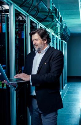 Man standing with laptop next to supercomputer