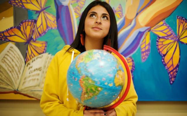 Woman holding globe looking upward