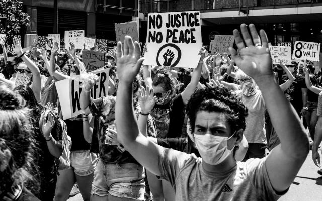 Protest with people holding signs and hands raised