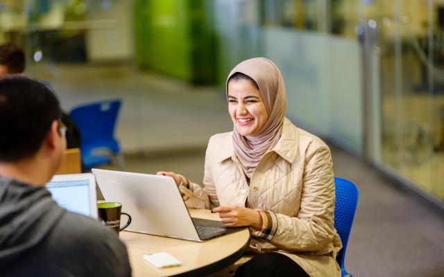 Two students with laptops talking