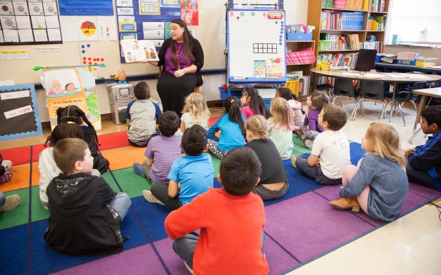 Teacher reading book to group of kids