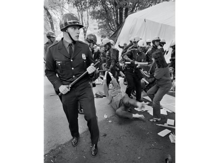 An officer watches as others beat student strikers