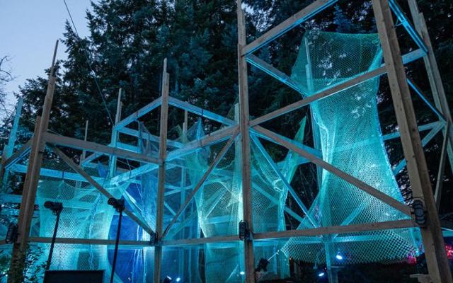 Illuminated wooden stage structure with fishing net sculptures at Pickathon
