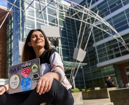 PSU student with laptop seated outside the engineering building in downtown Portland