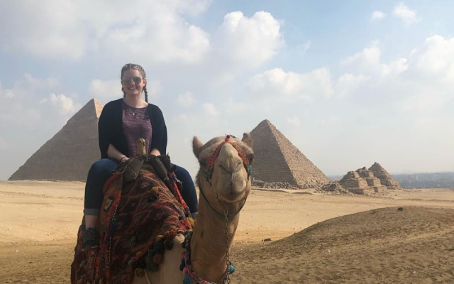 Arabic Studies student sitting on a camel in front of the pyramids at Giza, Egypt.