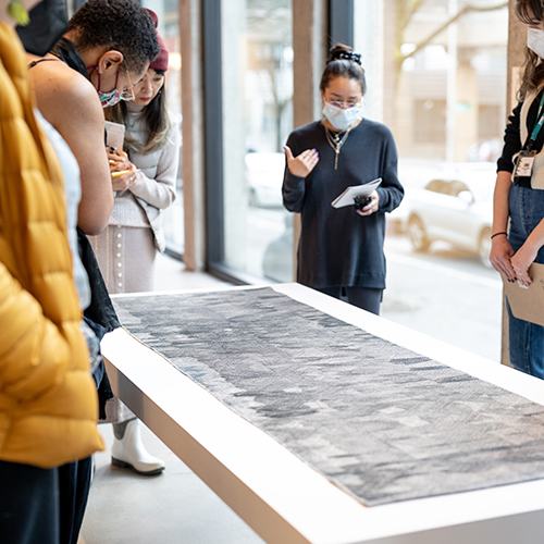 a small group of people listen to the gallery coordiator deliver a tour