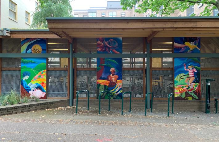 The whole mural is seen on the wall of the bike garage, with the three tall sections evenly spaced about six feet apart.