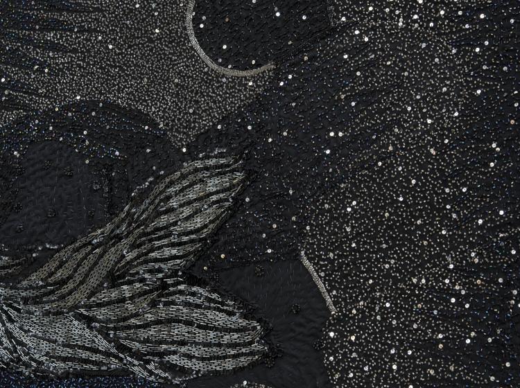 Close-up of a large, round multimedia artwork that is black and decorated in sequins and fabric, vaguely resembling stars and galaxies.