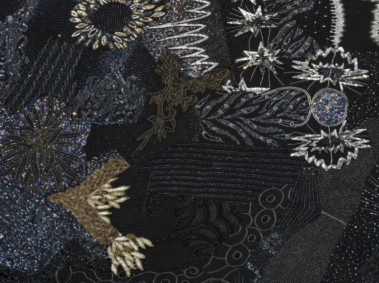 Close-up of a large, round multimedia artwork that is black and decorated in sequins and fabric, vaguely resembling stars and galaxies.