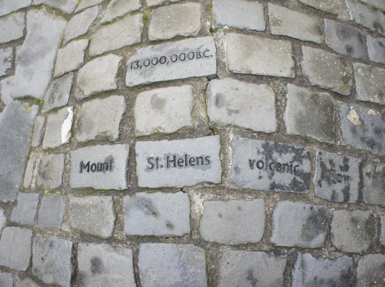 A view looking down at the mound. Some stones have words etched on them, such as "Mount," "St. Helens" and "Volcanic".