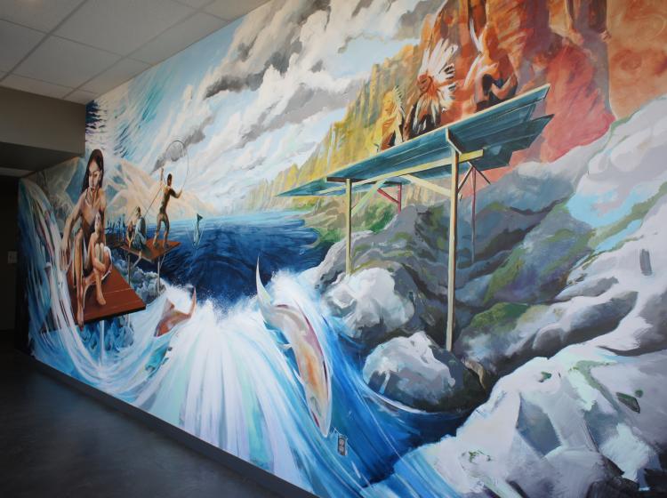 Angled shot of a section of mural in the hallway, depicting Native people fishing for salmon.