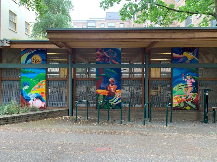 The whole mural is seen on the wall of the bike garage, with the three tall sections evenly spaced about six feet apart.