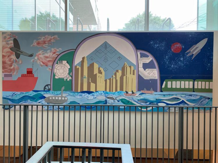 A mural is seen above a stairwell in the Engineering Building, an Art Deco-style composition with a stylized Portland skyline at center.
