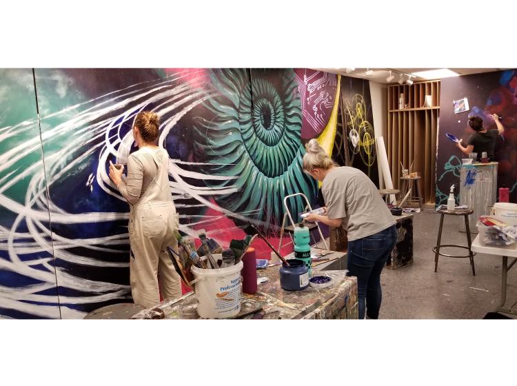 Students are seen working on the mural, which is being painted on separate tall panels that will be put together.