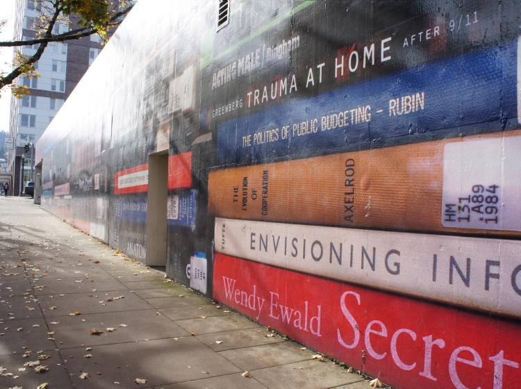 Close-up angled view of the mural, which covers the side of the 5th Avenue Cinema building in a huge photo of stacks of books.