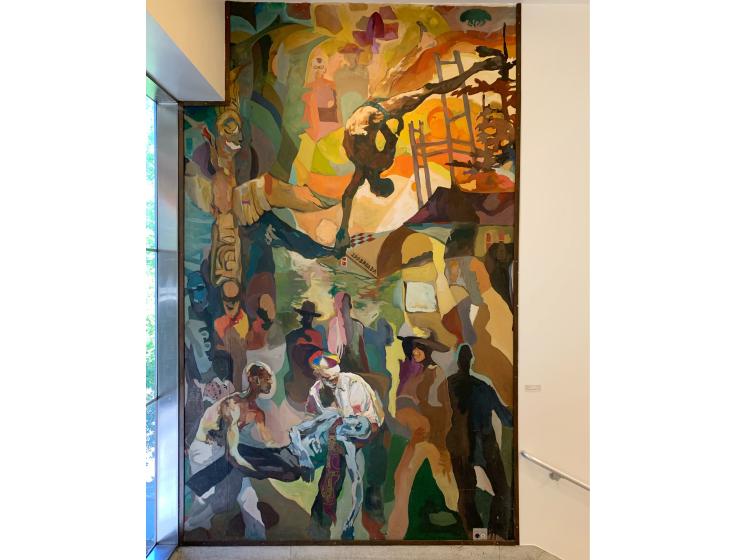 A floor-to-ceiling mural in a stairwell landing depicts Black figures in an abstract composition, with flood imagery and figures in the foreground carrying a dead body.