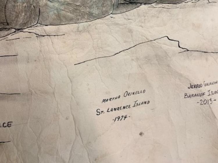 Close-up showing the signature of the artist who originally drew the walruses. It reads: Martha Okinello, St. Lawrence Island, 1974.