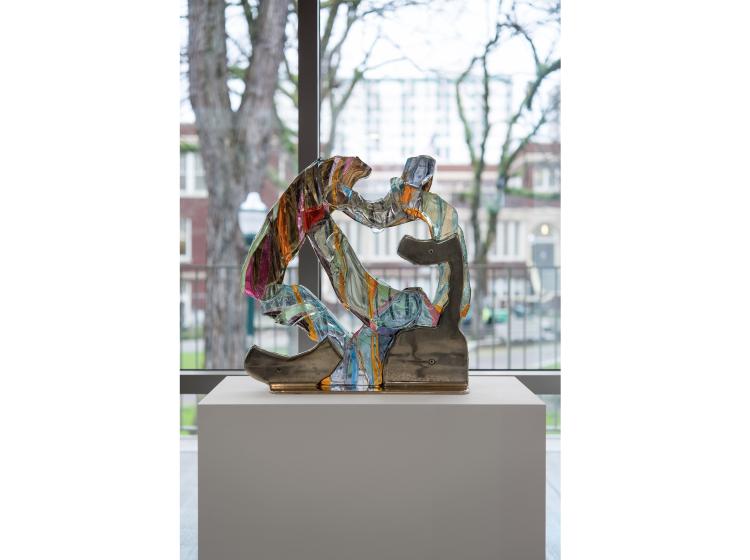 Straight-on view of the sculpture, with windows and view of Shattuck Hall in the background.