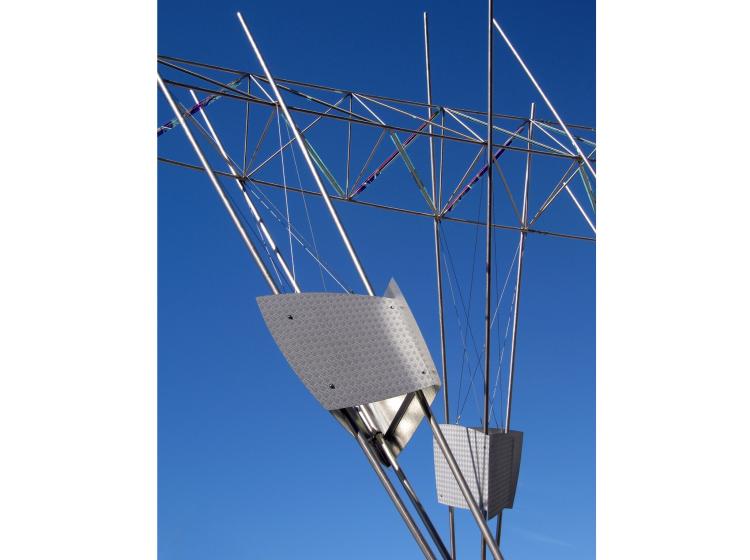 Close-up of a portion of the sculpture. Attached to the support poles are metal housings for lights.