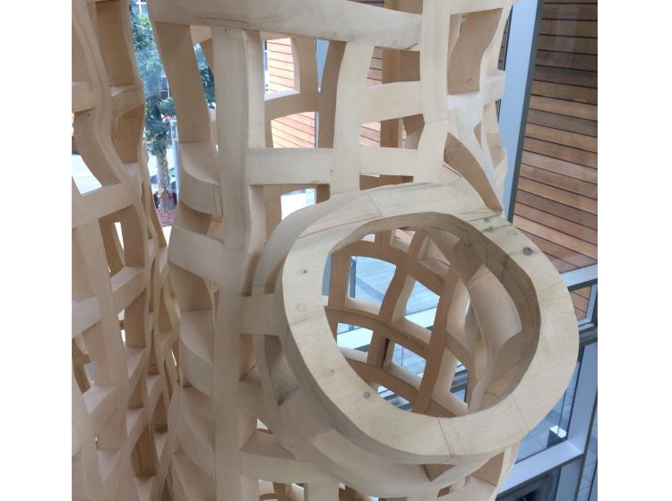 Close-up of a segment of the wooden sculpture, where a branch-like element diverges from the main form. 