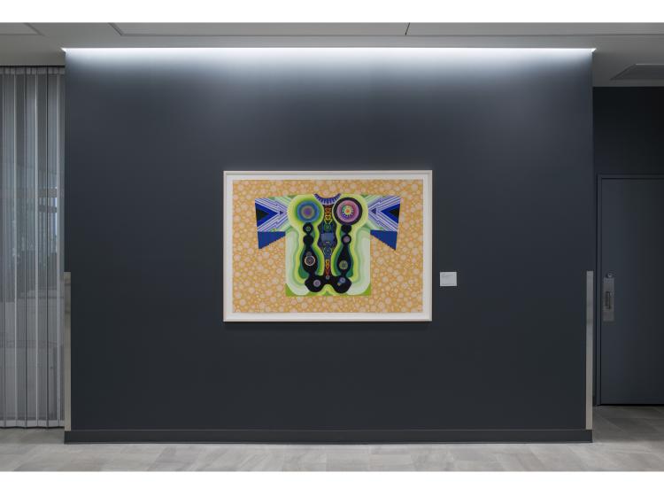 The artwork is seen framed on a dark grey wall.