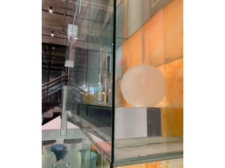 Detail shot of a section of the artwork, featuring a translucent glass ball in front of an orange background