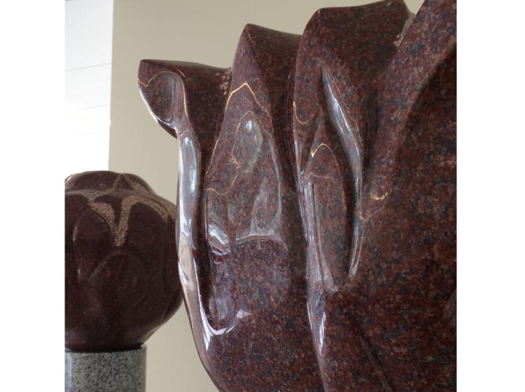 Close-up shot of the upper portion of one of the Beacons. The surface is carved with curving shapes and the color is a polished burgundy red.