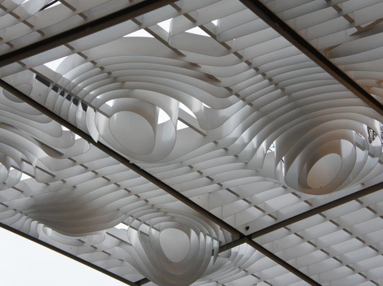 Close-up of the grid of curving white slats. They come together to form bulging round clusters that protrude down from the grid.