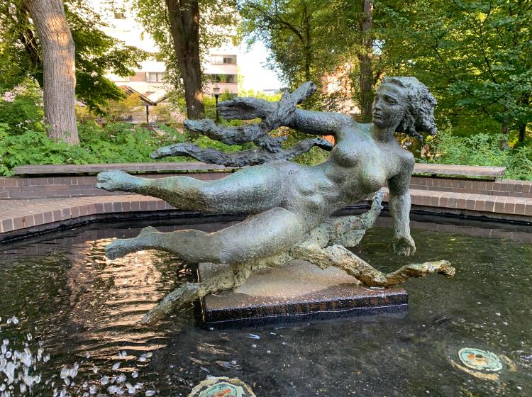 The sculpture and surrounding fountain are seen lit by morning light.