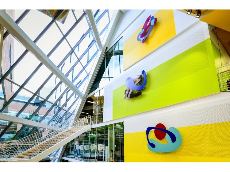 The artwork is seen at a dramatic angle, contrasted with the diagonal atrium windows of Karl Miller Center