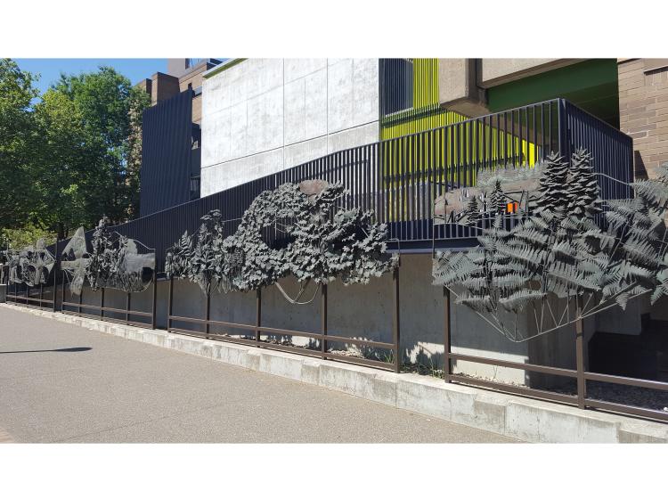 A section of the sculpture, depicting trees and ferns, is seen at a slight angle